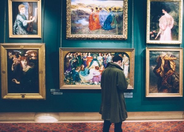 A man in front of a wall of paintings.