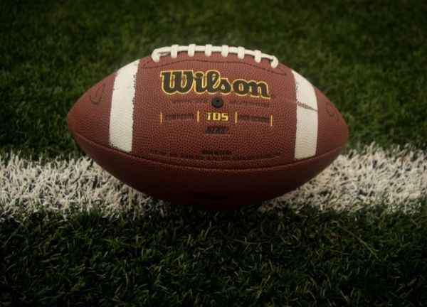 A football sitting on a white yard line.